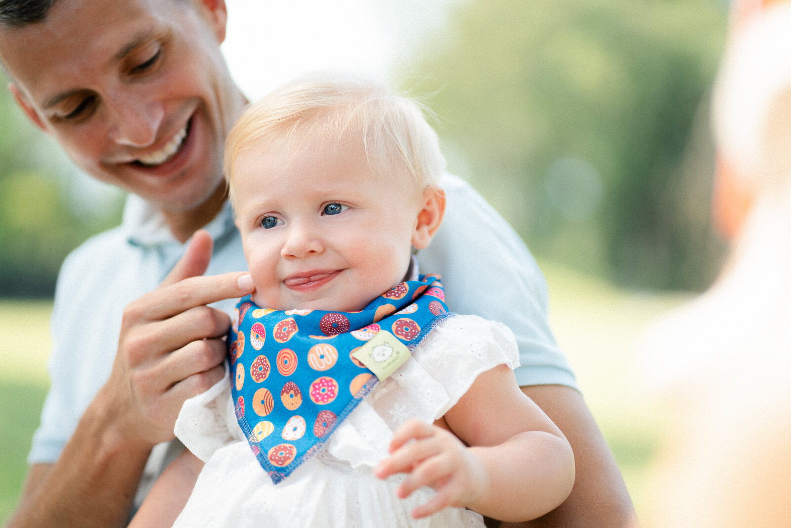 KeaBabies bandana bib on a smiling baby with parent outdoors — lifestyle e-commerce product photography Singapore