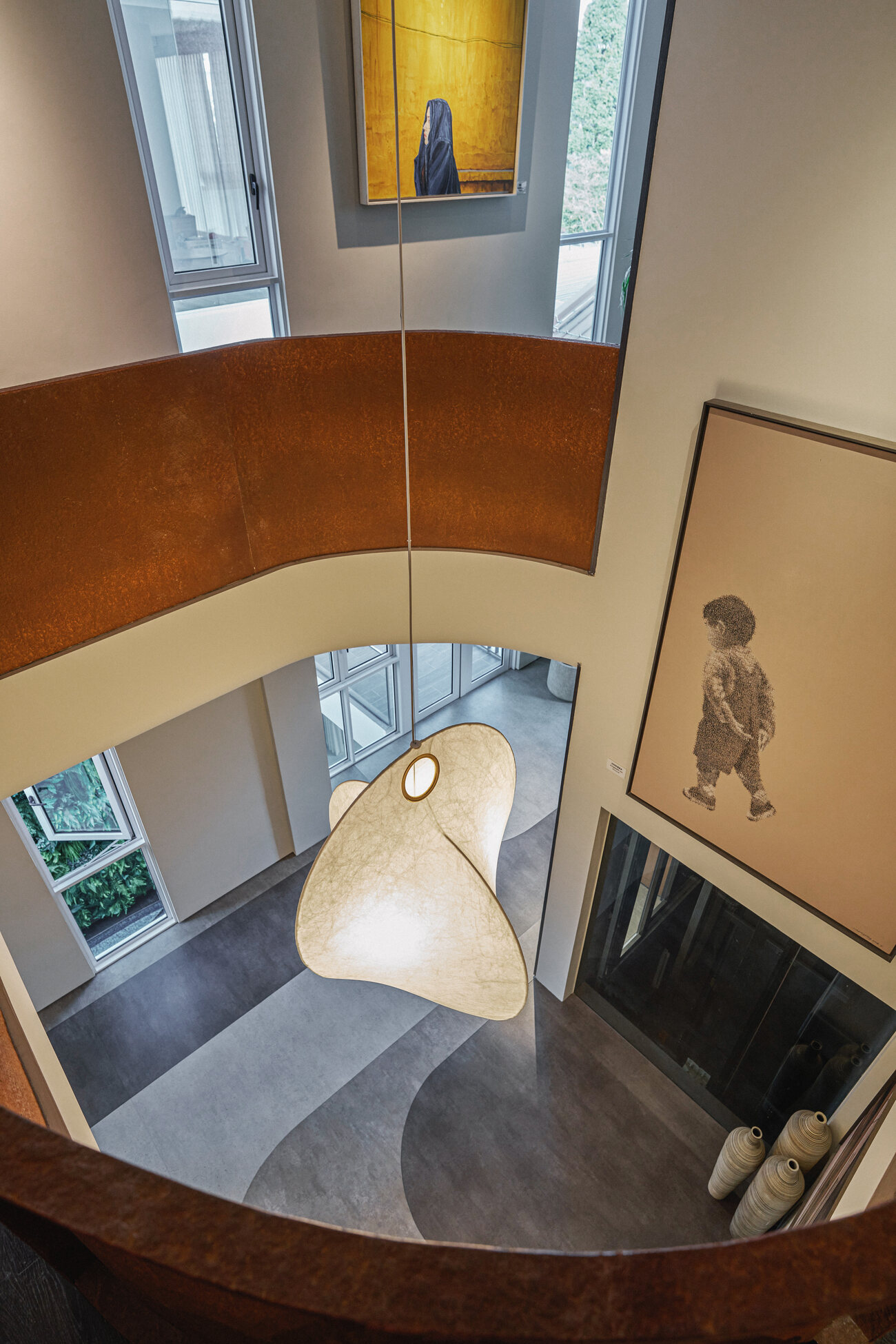 Telok Kurau residence architecture photography — a double-height void with curved walls, a pendant light and framed artwork