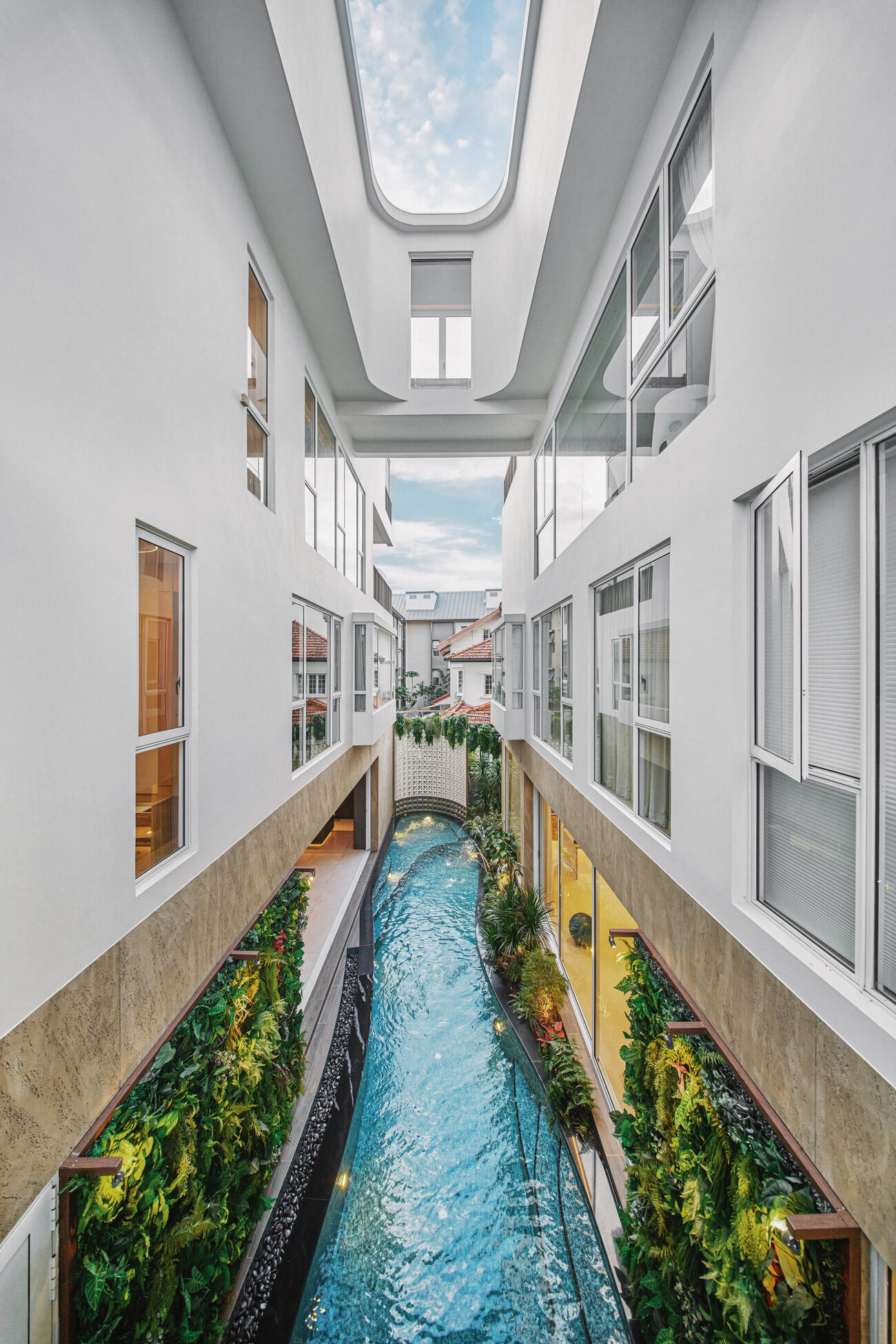 Telok Kurau residence interior photography — a naturally lit corridor with a koi water channel running beneath a skylight
