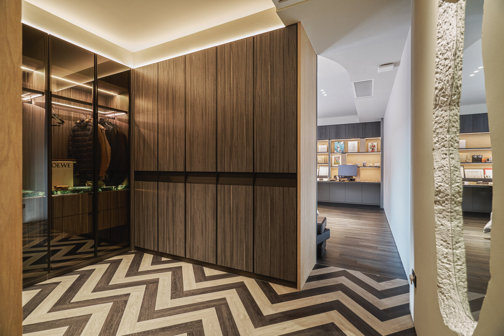 Telok Kurau residence interior photography — a walk-in wardrobe and dressing area in dark timber with a chevron floor and textured feature wall